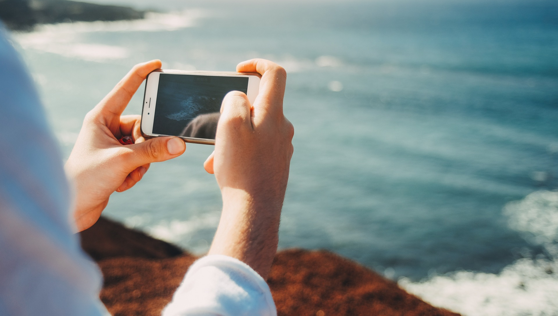 Ihminen ottaa kännykällä kuvan merestä.