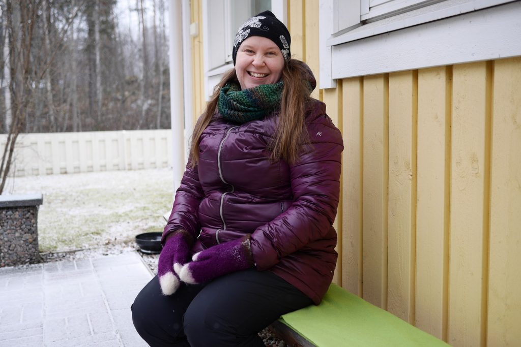 Hymyilevä Johanna istuu penkillä pihassa