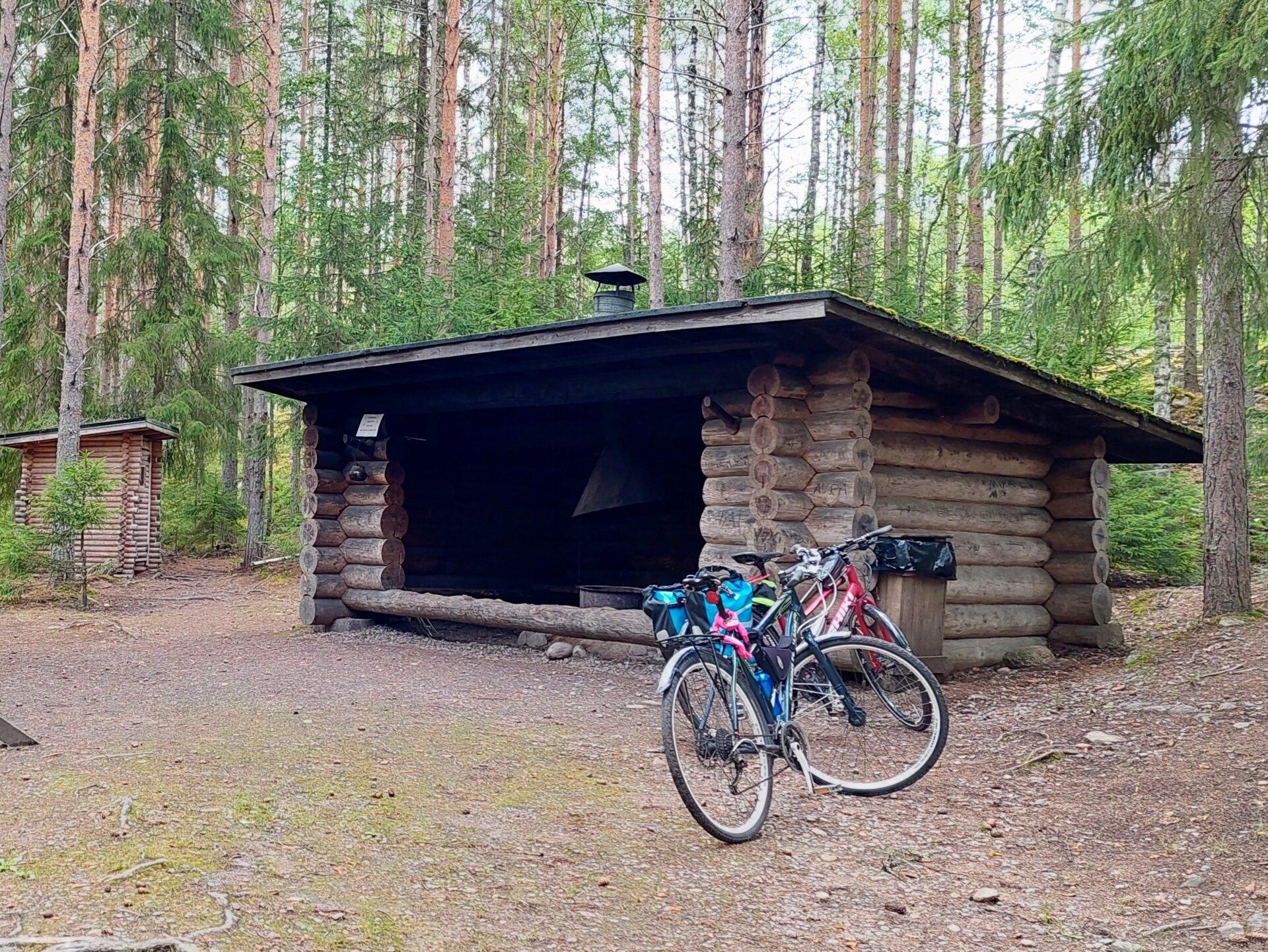 Hirsistä tehty laavu metsässä, edessä kaksi polkupyörää