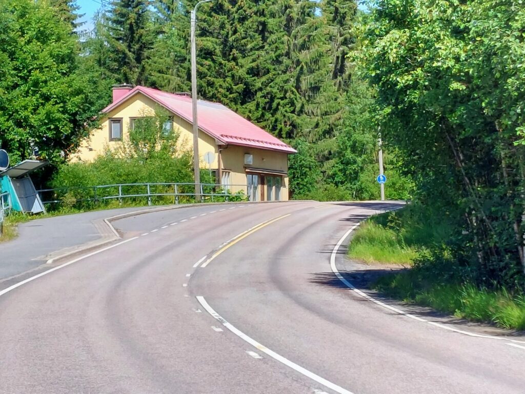 Autotie, mutka oikealle, mutkassa keltainen talo