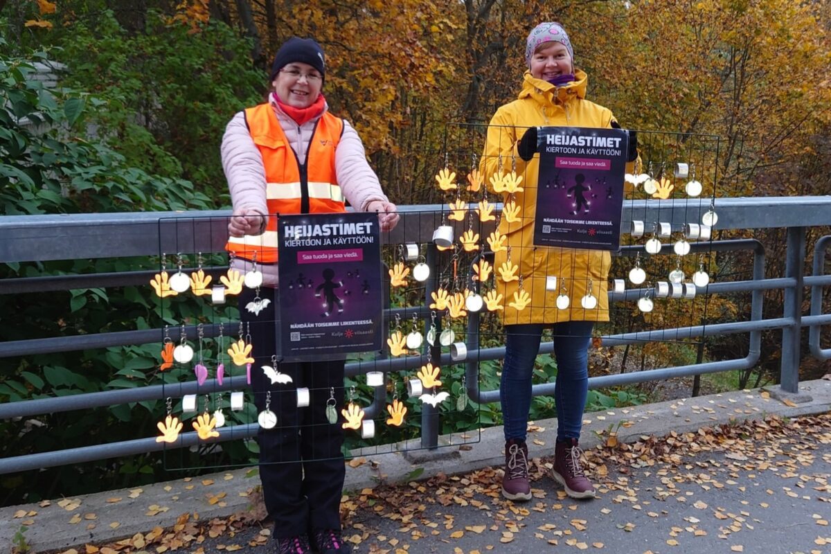 Kaksi naista ulkona käsissään telineet, joissa heijastimia.